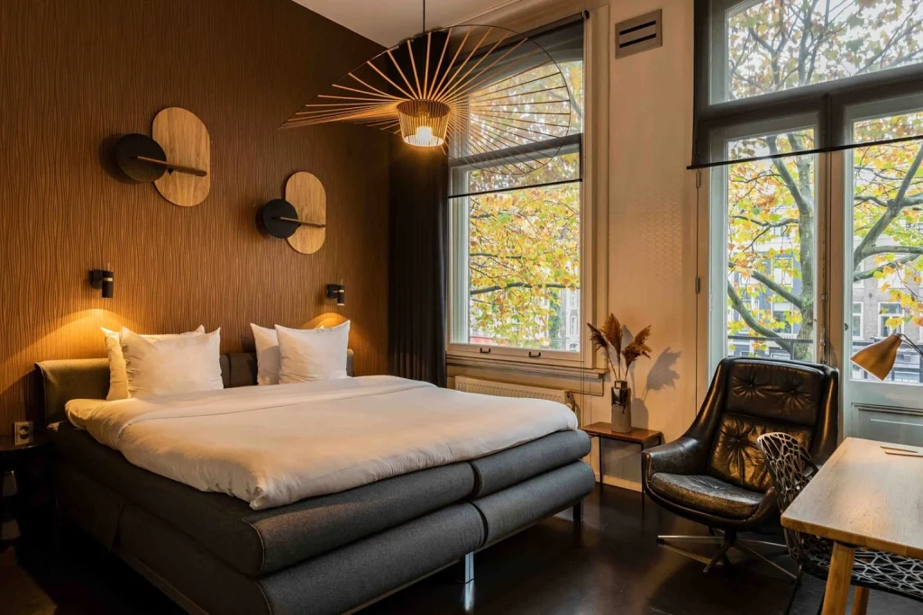 Contemporary boutique hotel room with large windows, designer lighting and canal-side views at Hotel V Frederiksplein – Houseboat Suites in Amsterdam.