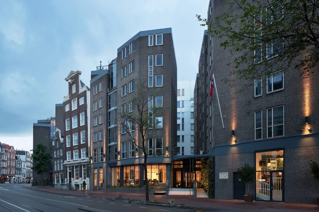 Contemporary brick façade and warmly lit entrance along a central Amsterdam street at Kimpton De Witt Amsterdam