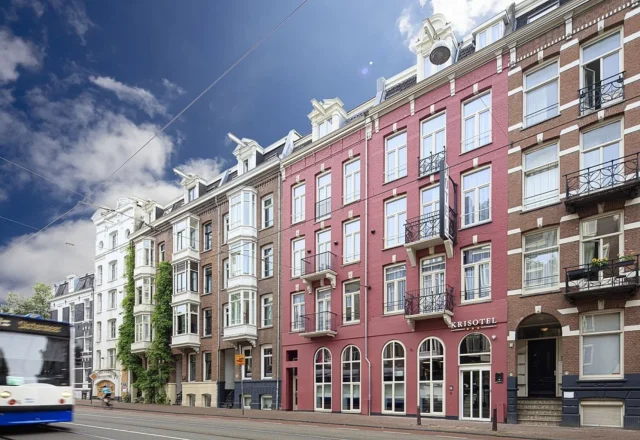 Historic red-brick hotel facade along a lively Amsterdam street at Krisotel Amsterdam