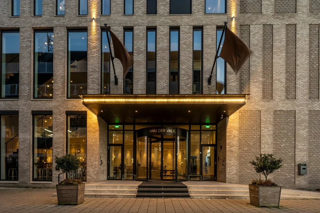 Modern brick hotel entrance with illuminated canopy and revolving doors, Van der Valk Hotel Amsterdam Amstel