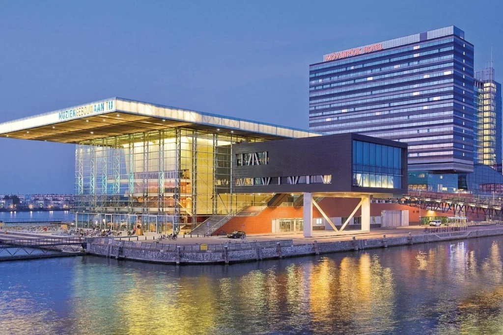 Waterfront view of Mövenpick Hotel Amsterdam City Centre beside the Muziekgebouw in Amsterdam