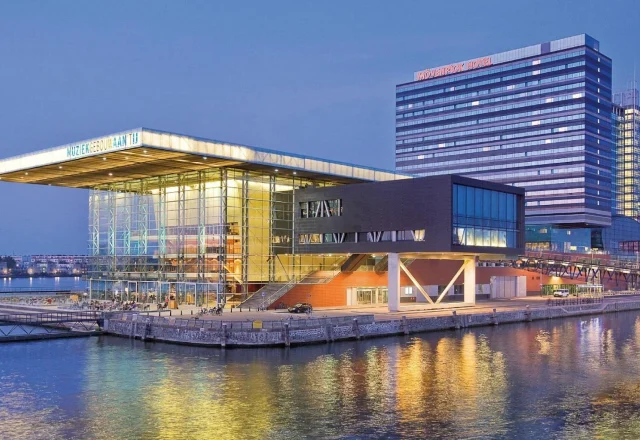 Waterfront view of Mövenpick Hotel Amsterdam City Centre beside the Muziekgebouw in Amsterdam