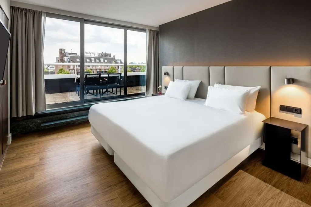 Modern double room with floor-to-ceiling windows and a private terrace overlooking the city at NH Amsterdam Caransa, Amsterdam