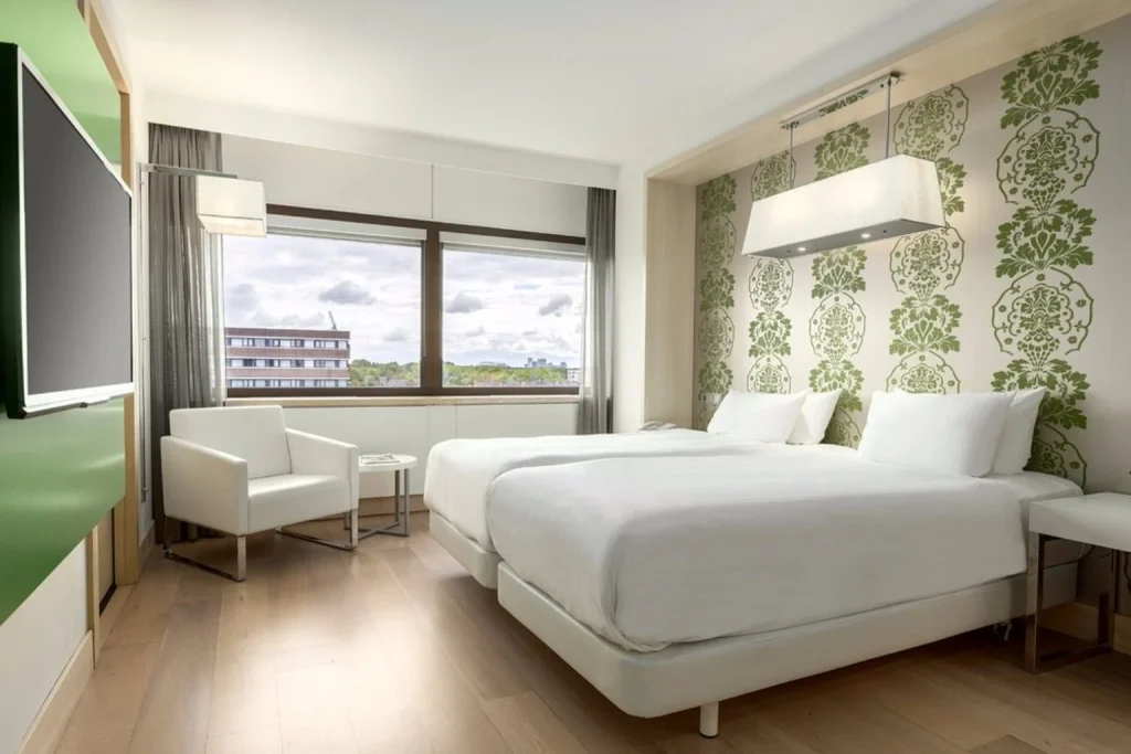 Bright modern room with twin beds, stylish green accents and large windows at NH Amsterdam Zuid, Amsterdam