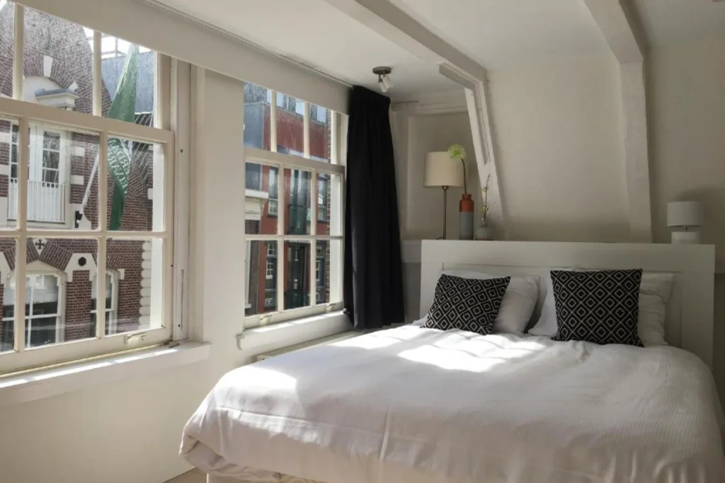 Sunlit guest room with large traditional windows overlooking the historic city streets at Nine Streets Inn, Amsterdam
