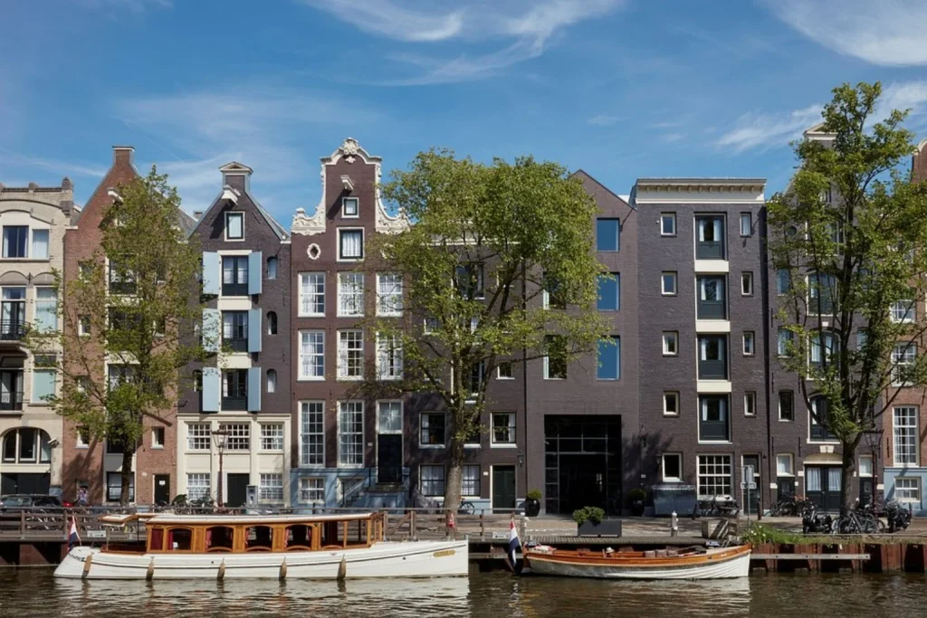 Historic canal houses with traditional boats moored along the waterfront, Pulitzer Amsterdam, Amsterdam