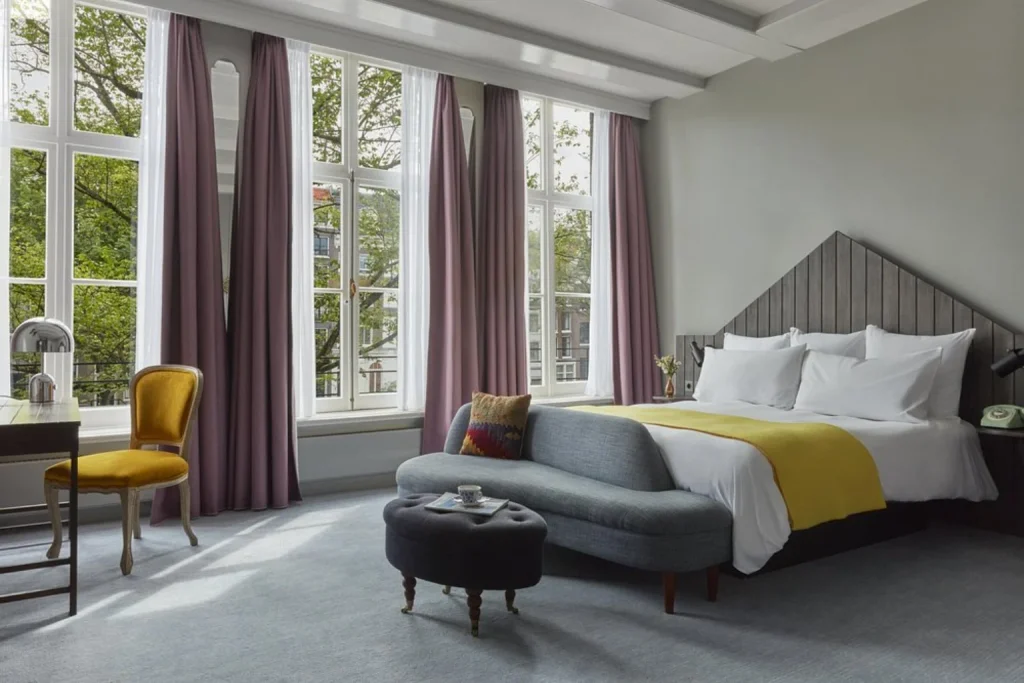 Spacious light-filled room with floor-to-ceiling windows, refined furnishings and views of leafy surroundings at Pulitzer Amsterdam, Amsterdam