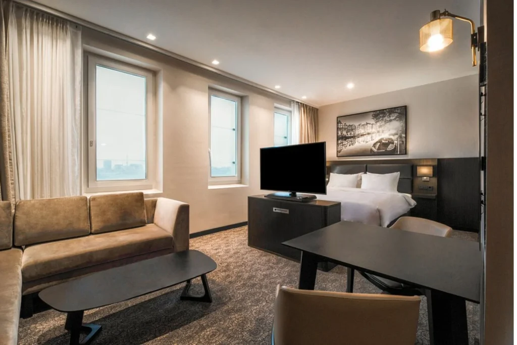 Contemporary hotel suite with a comfortable double bed, separate seating area and dining space at Radisson Hotel & Suites Amsterdam South, Amsterdam