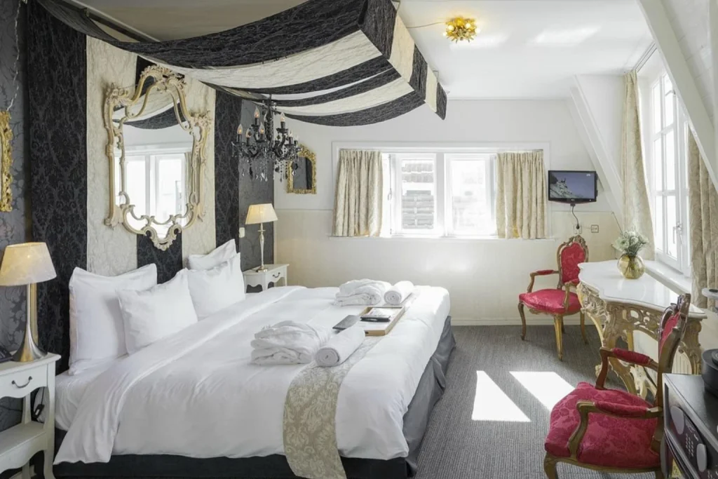 Romantic bedroom with ornate mirrors, black chandelier and red velvet chairs, Rosalia’s Menagerie Inn, Amsterdam