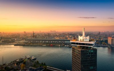Aerial view of Sir Adam Hotel (A’DAM Tower) with Amsterdam skyline and waterfront at sunset