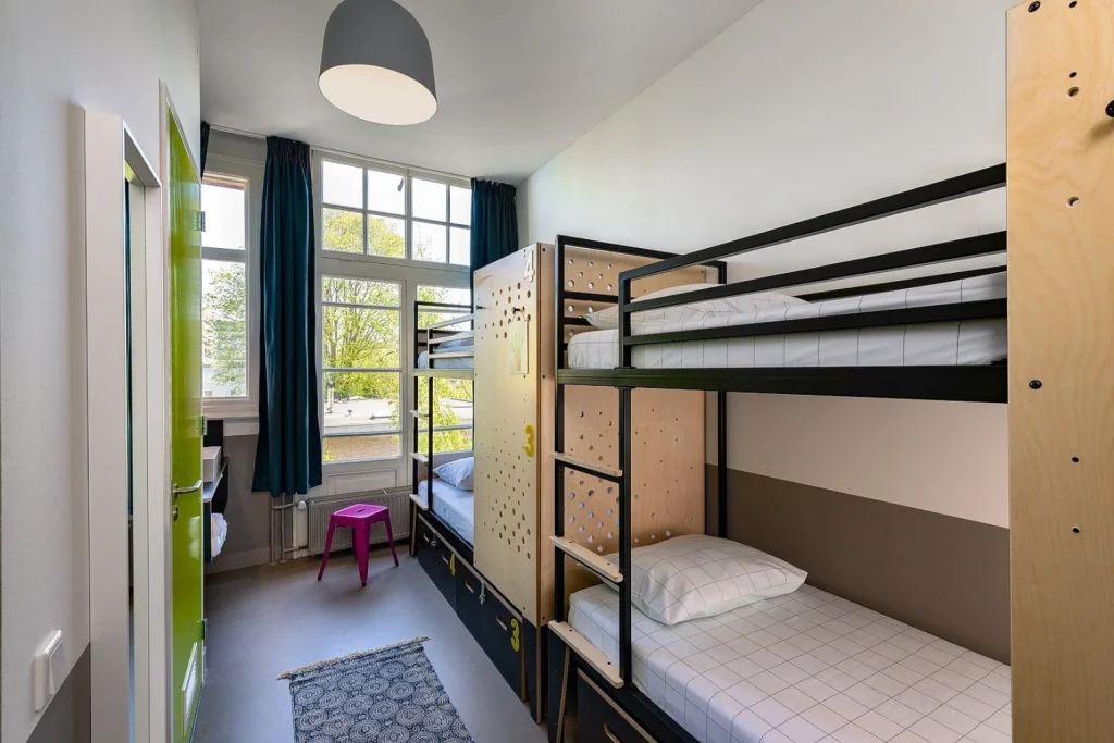 Bright hostel room with modern bunk beds, individual sleeping spaces and large windows at Stayokay Hostel Vondelpark, Amsterdam