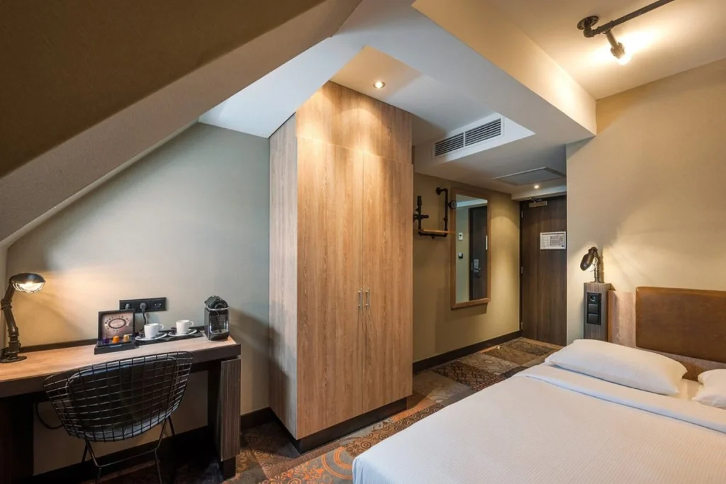 Comfortable double guest room with a work desk, warm interior and modern amenities at The Alfred Hotel, Amsterdam