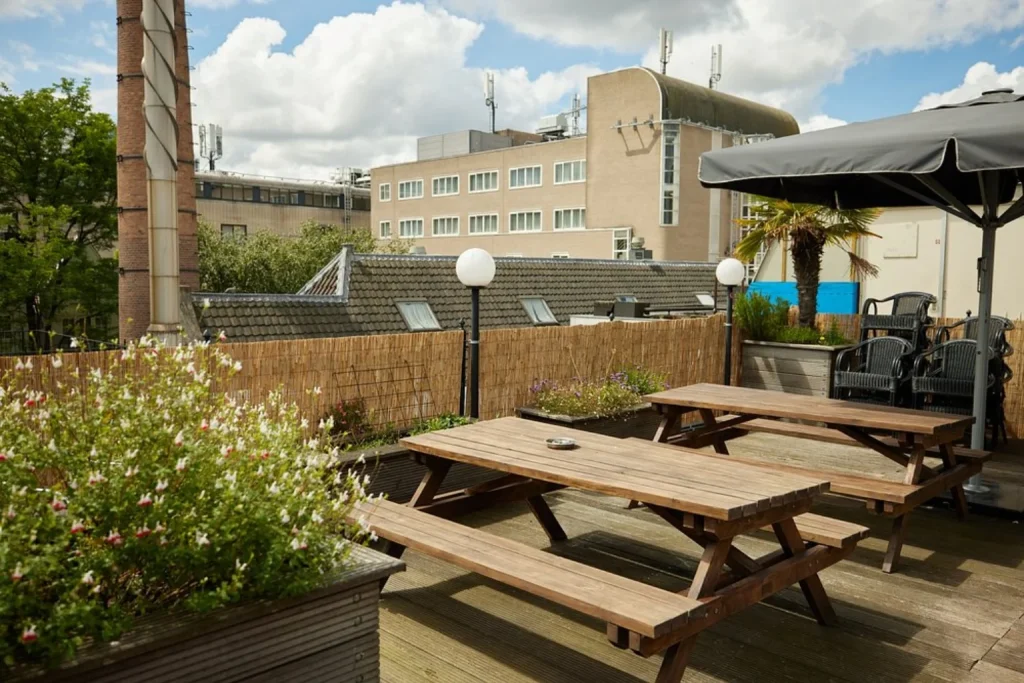 Rooftop terrace at The Bulldog Hotel Amsterdam with wooden picnic tables and outdoor seating