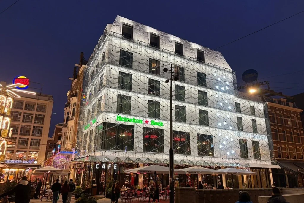Modern illuminated glass façade of The Diamond at Leidseplein Amsterdam at night.