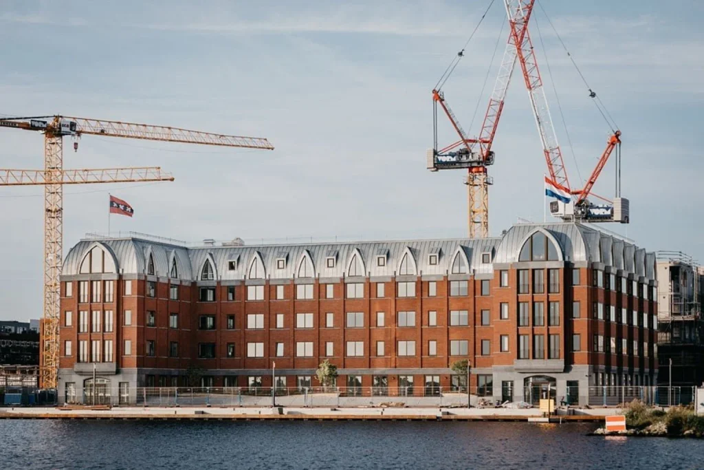 Modern waterfront building with distinctive brick facade and harbor views at The July – BOAT & CO, Amsterdam