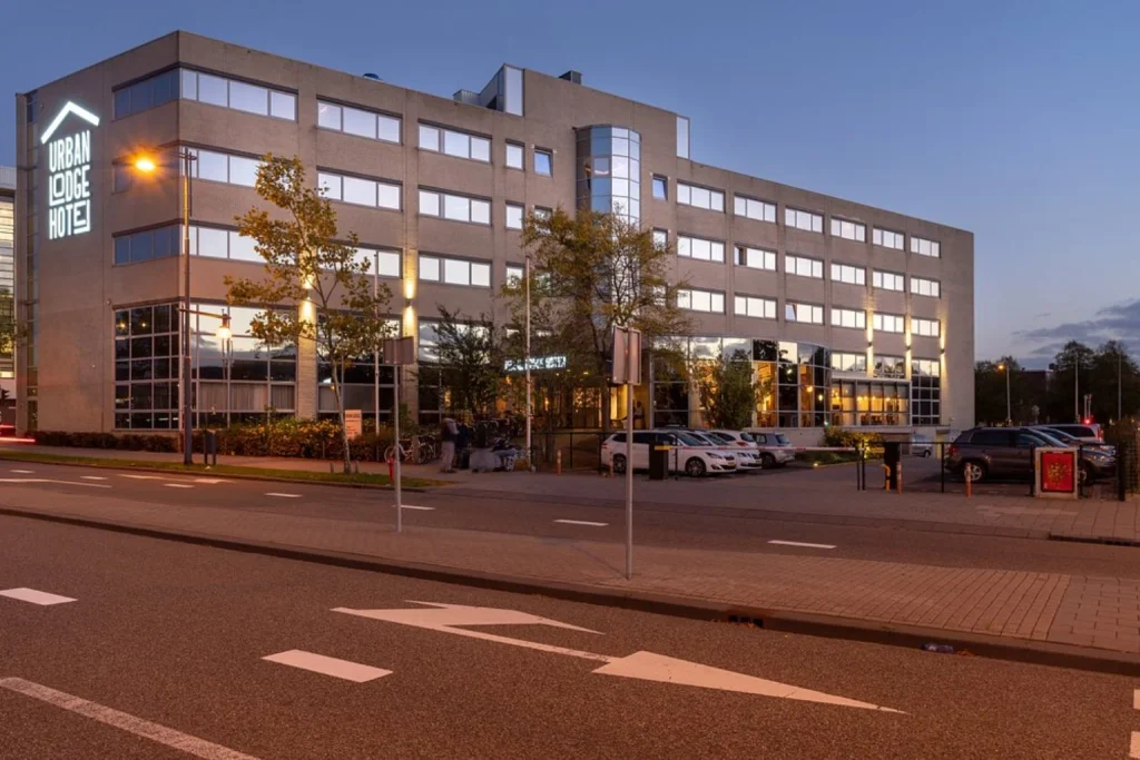 Contemporary hotel building with illuminated signage and a welcoming evening atmosphere at Urban Lodge Hotel, Amsterdam