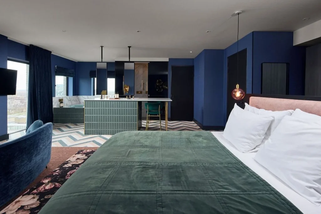 Spacious modern guest room with a king bed, deep blue interiors and open bathroom area at Van der Valk Hotel Amsterdam Amstel, Amsterdam